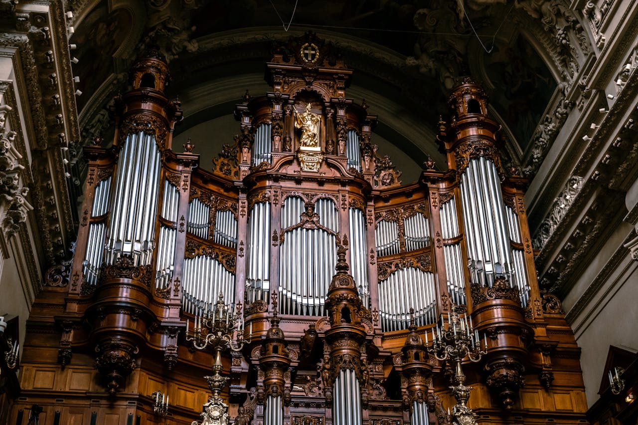 Intricate wood and metal pipe organ in an ornate church, showcasing religious craftsmanship.